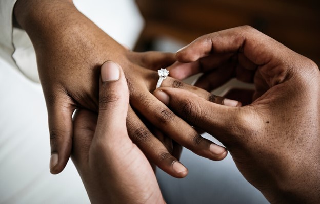 Man placing an engagement ring on a women's finger